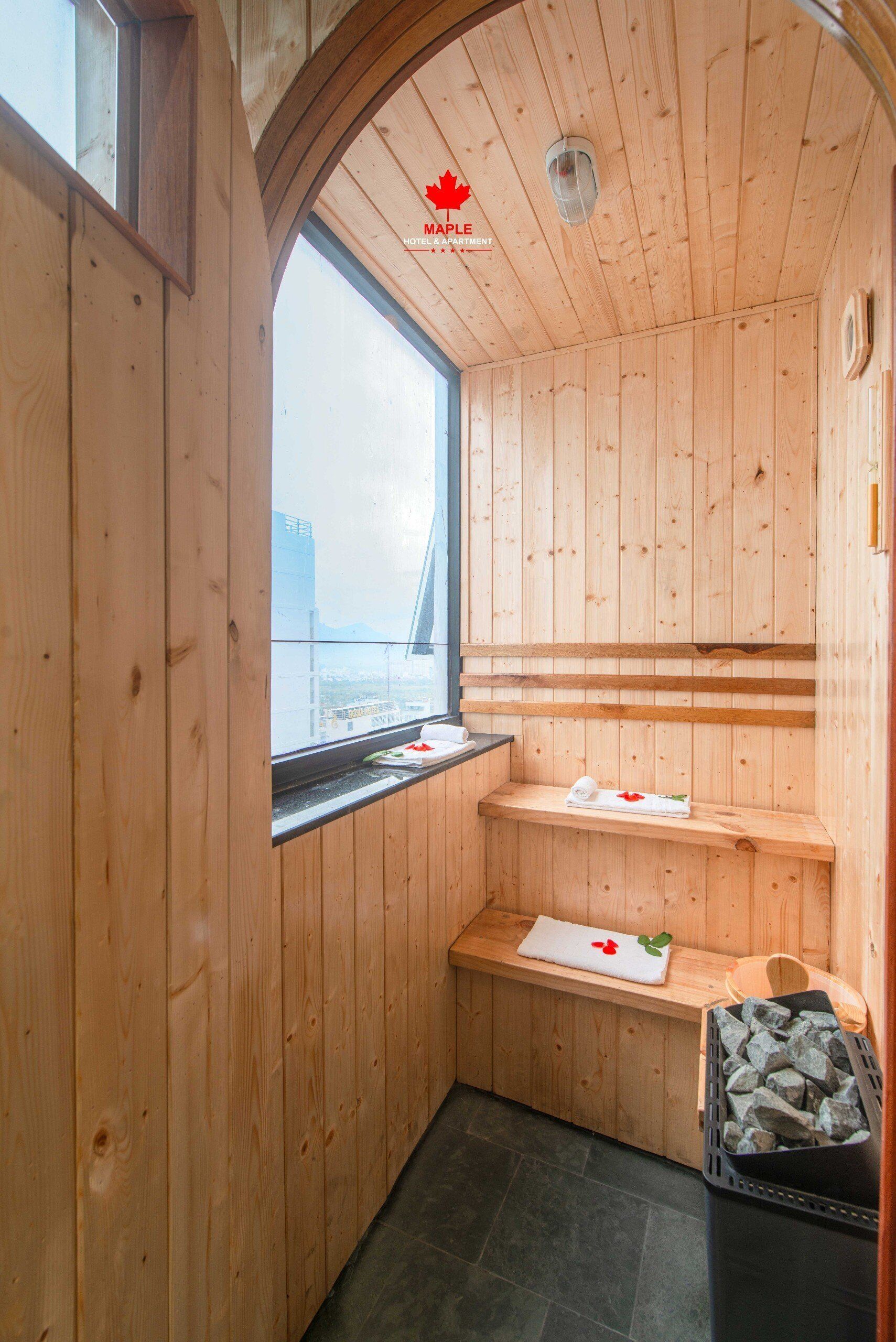 Un sauna de madera con ventana, un banco y un estante con toallas.