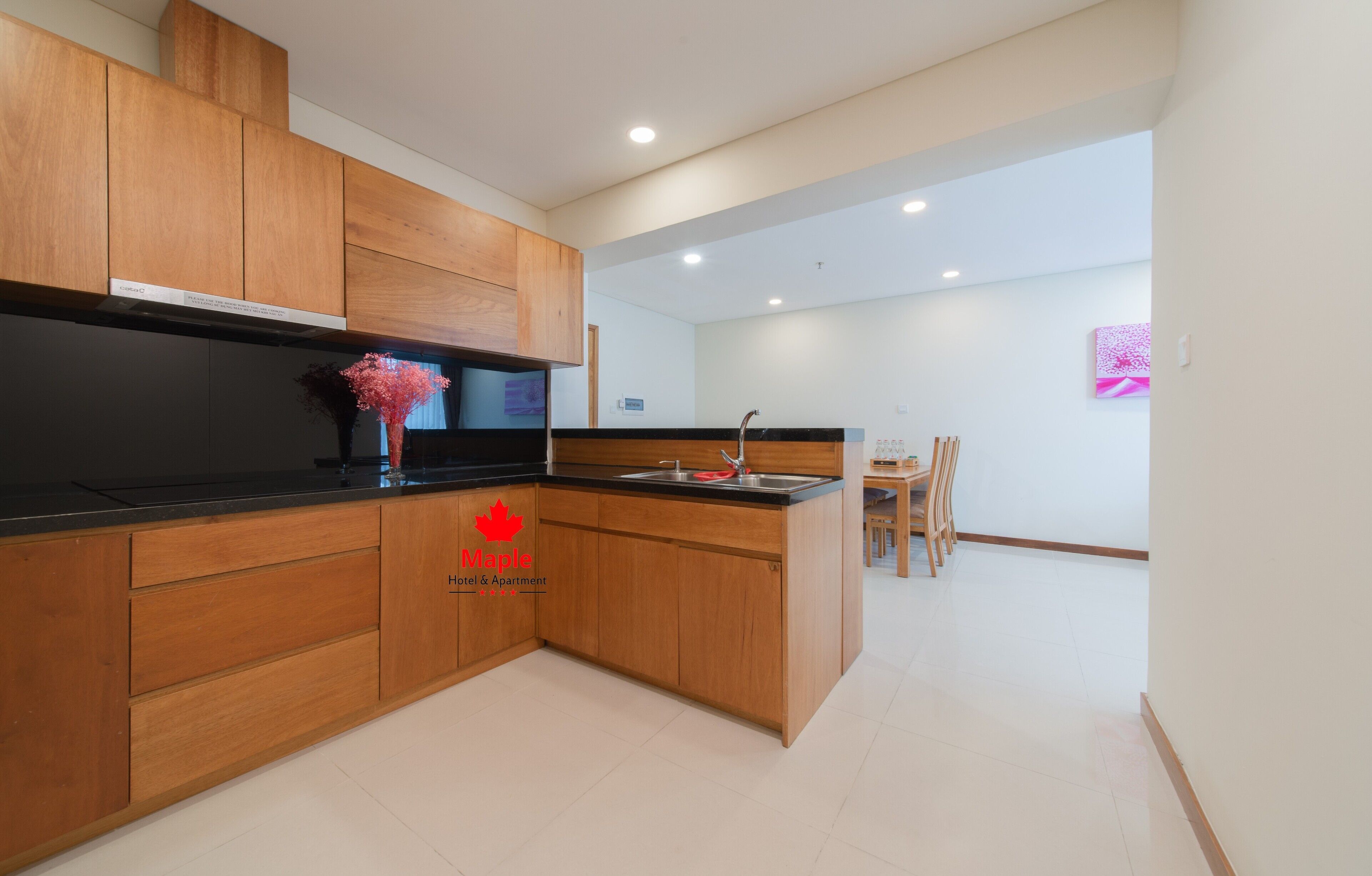 A modern kitchen with wooden cabinets, a black countertop, and a built-in stove.
