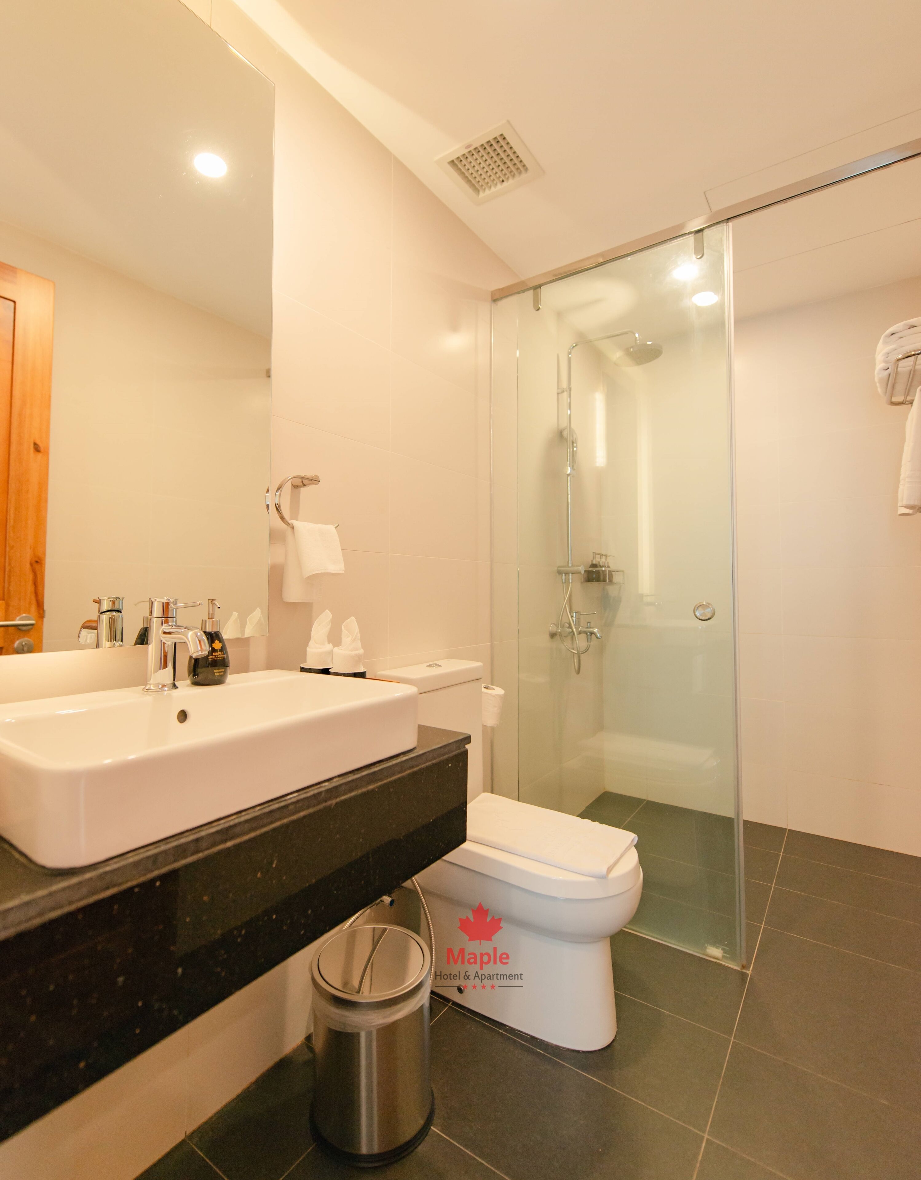 Un baño moderno con un lavamanos grande, inodoro y cabina de ducha de vidrio.