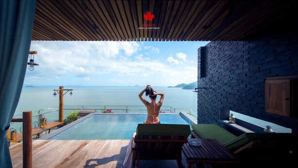 A wooden deck with a pool, a lounge chair, and a view of the sea. - Maple Hotel & Apartment (Nha Trang)