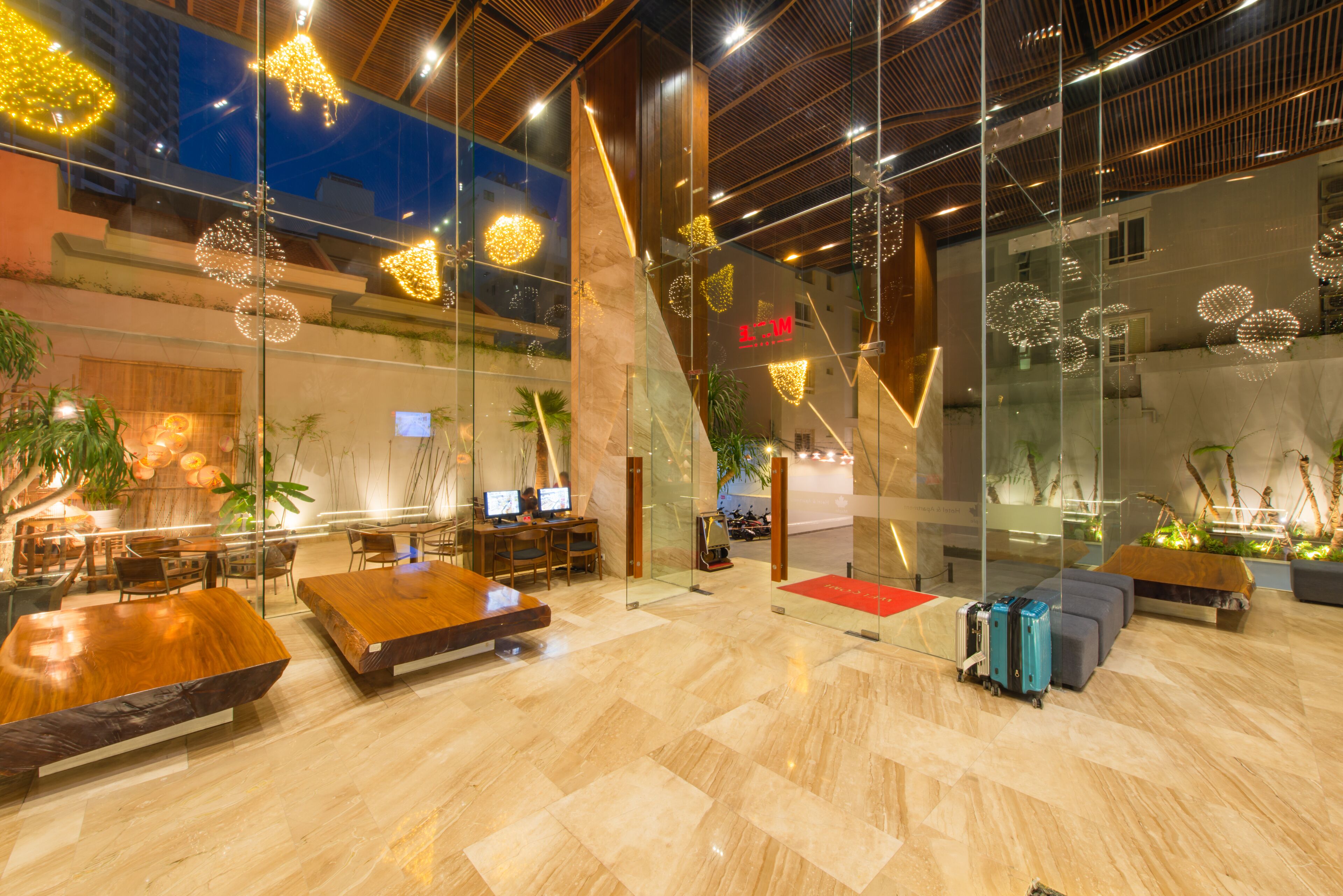 A modern lobby with a wooden reception desk, seating area, and glass walls.
