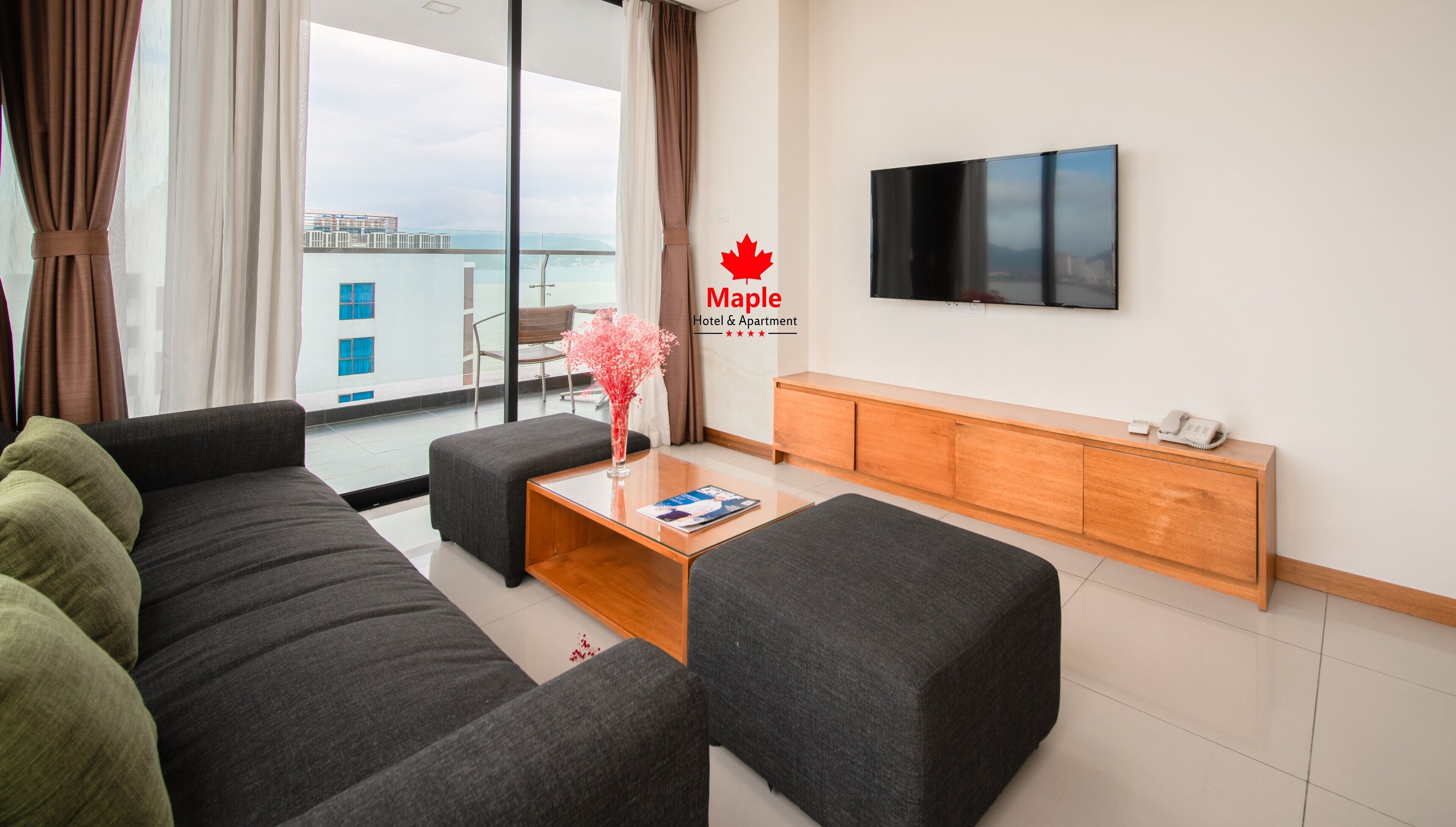 Uma sala de estar moderna com um sofá cinzento, uma mesa de centro de madeira e uma TV de tela plana fixada na parede.