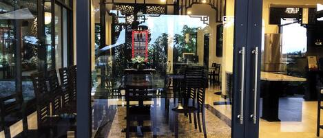 A modern dining area with a patterned floor, black furniture, and a decorative wall.