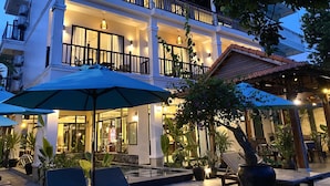A multi-story hotel with balconies, outdoor seating, and a pool area. - The Quin Riverside Villa (Da Nang)