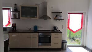 Een moderne keuken met een inbouwoven, een koffiezetapparaat en een waterkoker op het aanrecht.