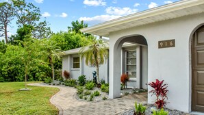 A two-story house with a number 916 on the front wall, surrounded by a landscaped garden with various plants and a curved driveway. - 🪷Lotus House-Relaxation-few Minutes to🏖️ Beaches-🏊Heated Pool (Venice)