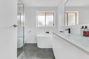 A modern bathroom with a glass shower enclosure, a freestanding bathtub, and a white vanity with a black faucet. - Echuca Moama Holiday Accommodation 1 (Echuca)