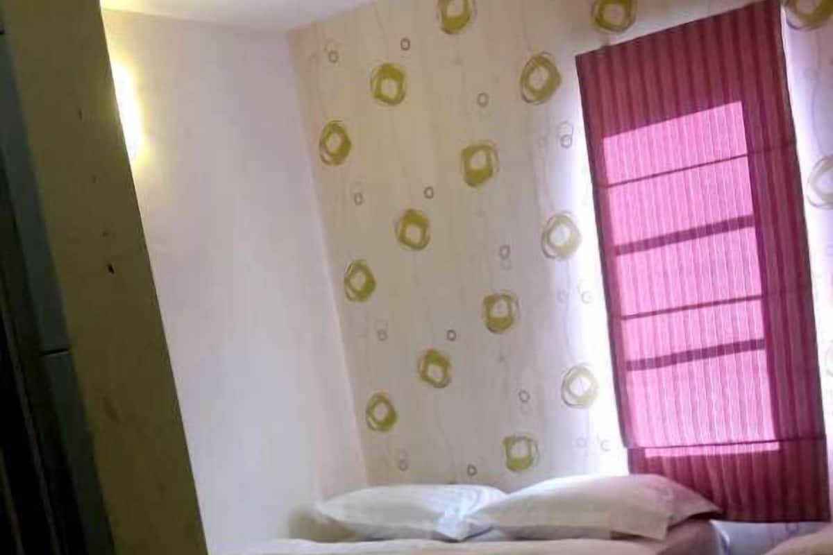 Una habitación con dos camas, una ventana con cortinas rosadas y una pared con un diseño de círculos amarillos.