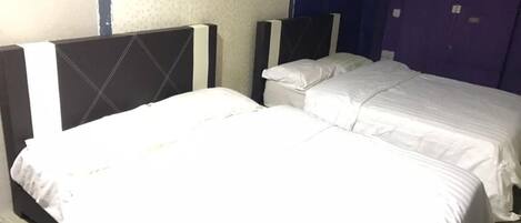 A hotel room with two beds, a large window, and a blue wall.