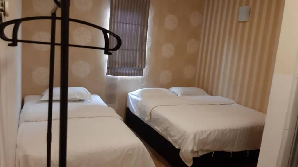 A room with two beds, a window with blinds, and a curtain.