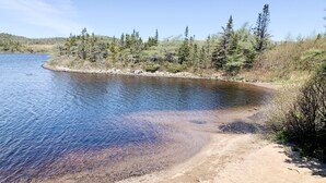 A river with clear water, surrounded by trees and a sandy shore. - Calming Cabin Retreat (Outside North Harbour)