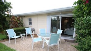 A patio with a table and four chairs, a sliding glass door, and a small garden area. - Jamaica Royale Siesta Key Condo 109 (Siesta Key)