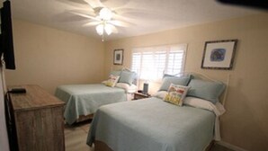 A bedroom with two single beds, a ceiling fan, and a wooden cabinet. - Jamaica Royale Siesta Key Condo 109 (Siesta Key)