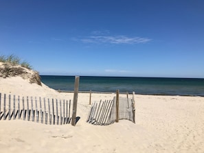 A sandy beach with a wooden fence and a clear view of the ocean. - CLEAN, Walk To Beach, Ferries, Downtown, Newly Renovated House, Pet Friendly (Yarmouth)