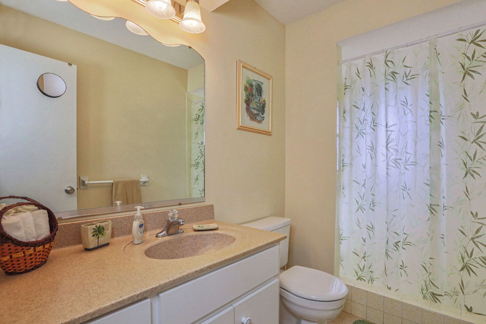 Ein Badezimmer mit Waschbecken, Spiegel, Toilette und Duschvorhang.