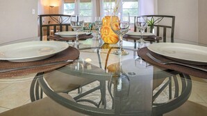 Ein Essbereich mit einem Glastisch, Stühlen und einer Vase im Sonnen-Design.