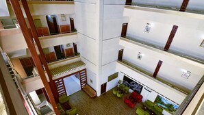 Un hôtel à plusieurs niveaux, avec un atrium central, de nombreux balcons et divers espaces aménagés pour se détendre.