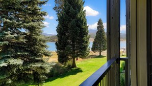 Ein Balkon mit Blick auf einen See, Bäume und ferne Berge.