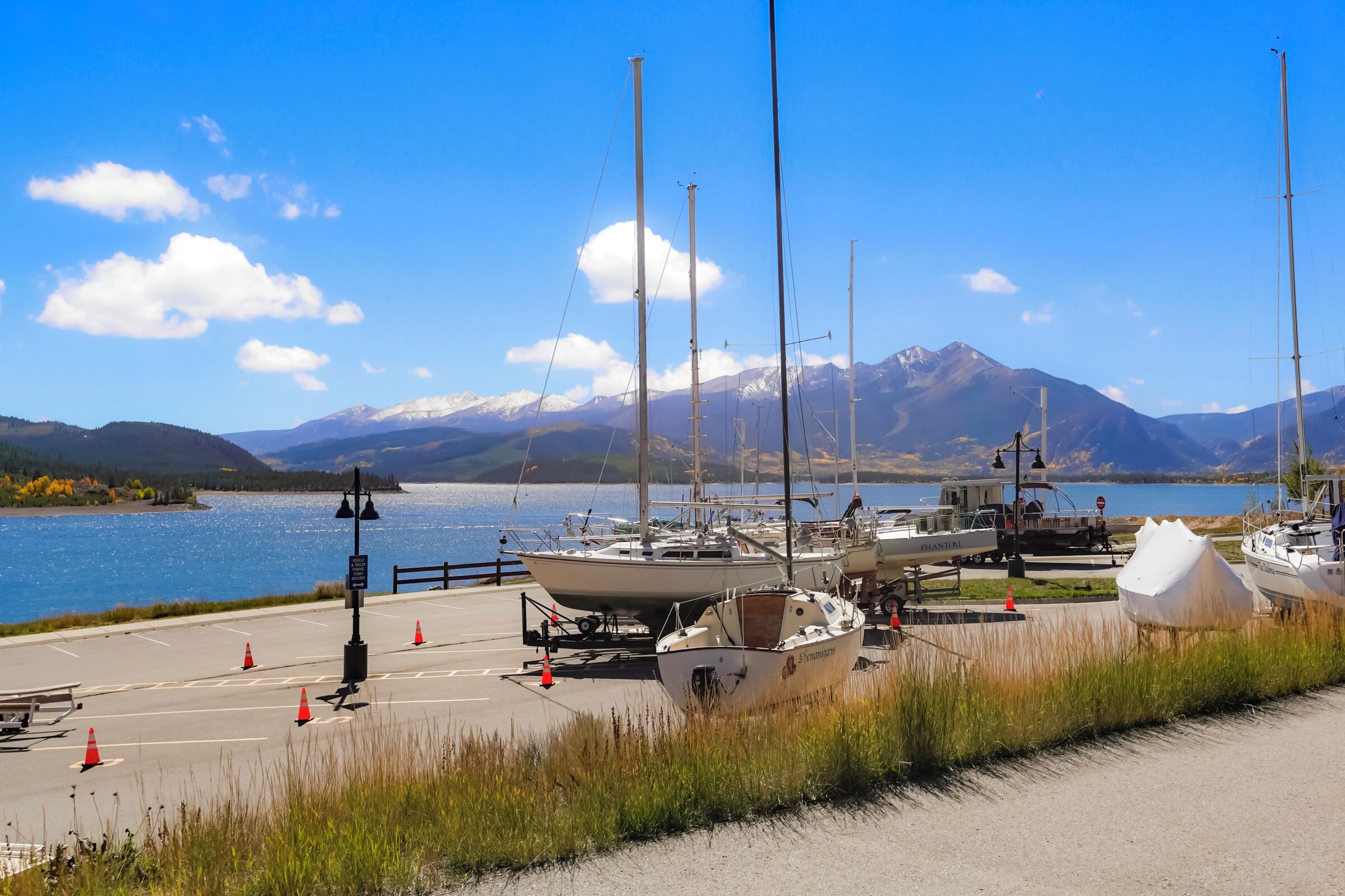 A marina with boats docked, a clear sky, and mountains in the background.