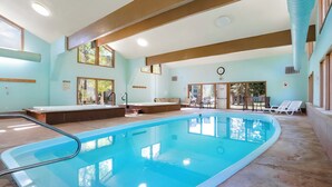 Ein Schwimmbad mit Dachfenster, Liegestühlen und einer Lounge mit Sesseln.