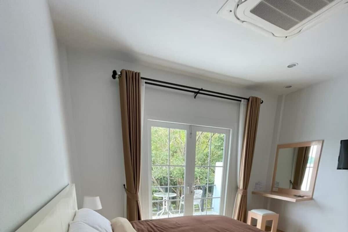 Ein Schlafzimmer mit Bett, Nachttisch, Spiegel und Blick ins Freie.