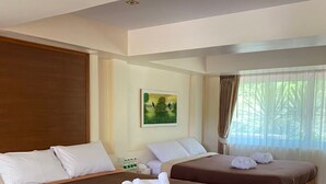 Une chambre d’hôtel avec deux lits, des têtes de lit en bois, un tableau au mur et une fenêtre avec des rideaux.