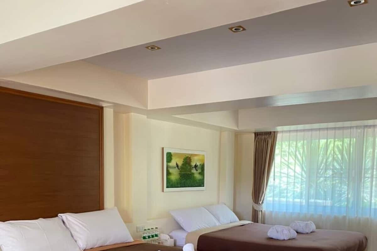 Ein Hotelzimmer mit zwei Betten, Holz-Kopfteilen, einem Bild an der Wand und einem Fenster mit Vorhängen.