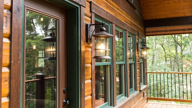A wooden cabin with a porch, large windows, and a door. - Elevate Your Stay! (Crosslake)