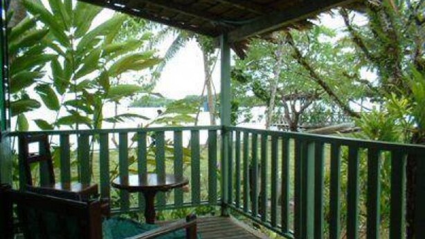 A wooden deck with a green railing, a bench, and a table.