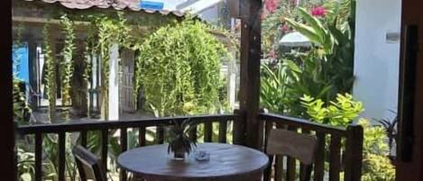A wooden deck with a round table and chairs, surrounded by a wooden railing.