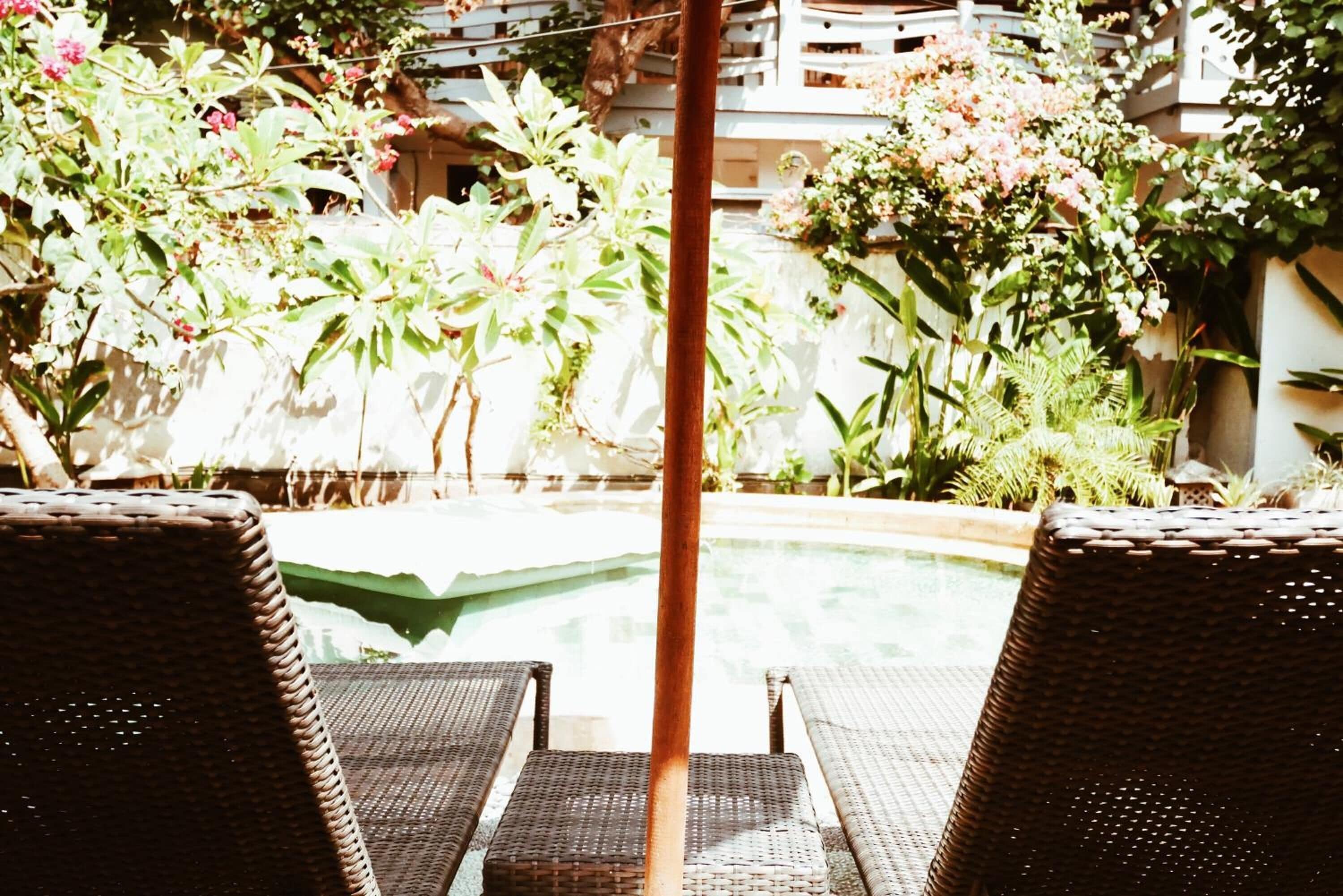 A poolside area with wicker lounge chairs and lush greenery.