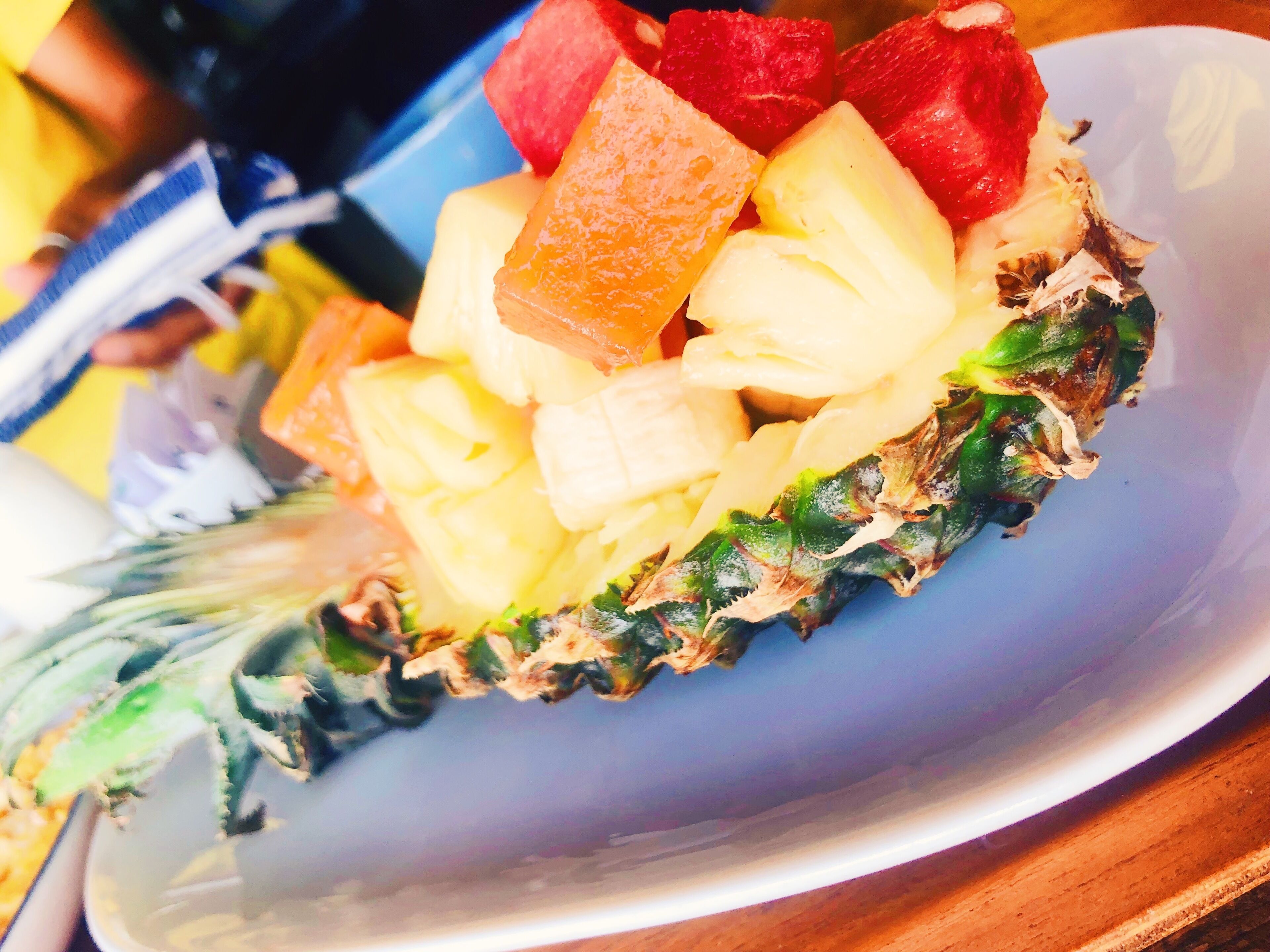 A plate with a variety of fruits including watermelon, pineapple, and possibly mango, arranged on a bed of greens.