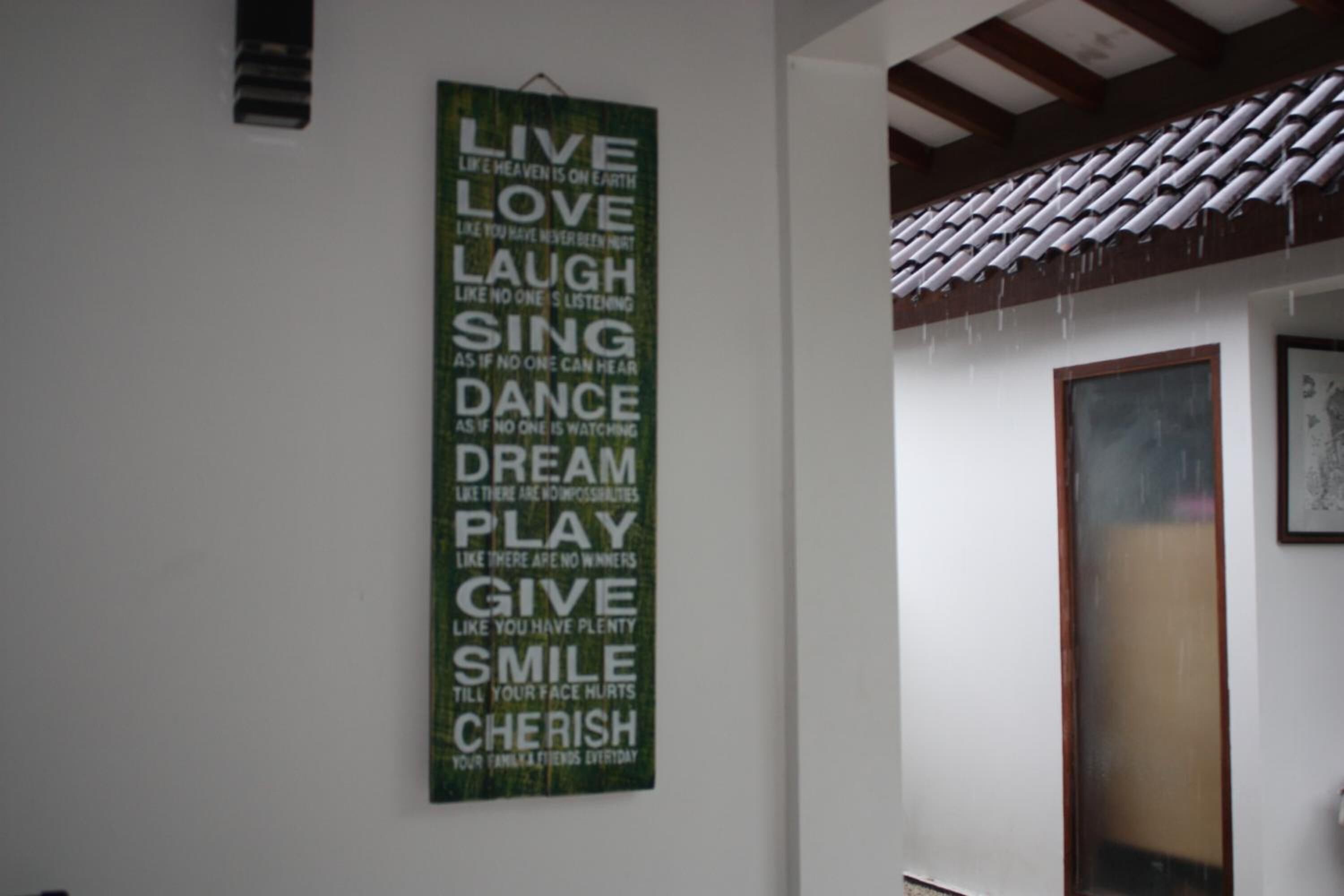 A room with a green motivational poster on the wall, a tiled ceiling, and a framed picture.