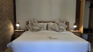 A bedroom with a bed, wooden headboard, and two bedside tables with lamps. - Kalua Boutique Bungalows (Gili Trawangan)