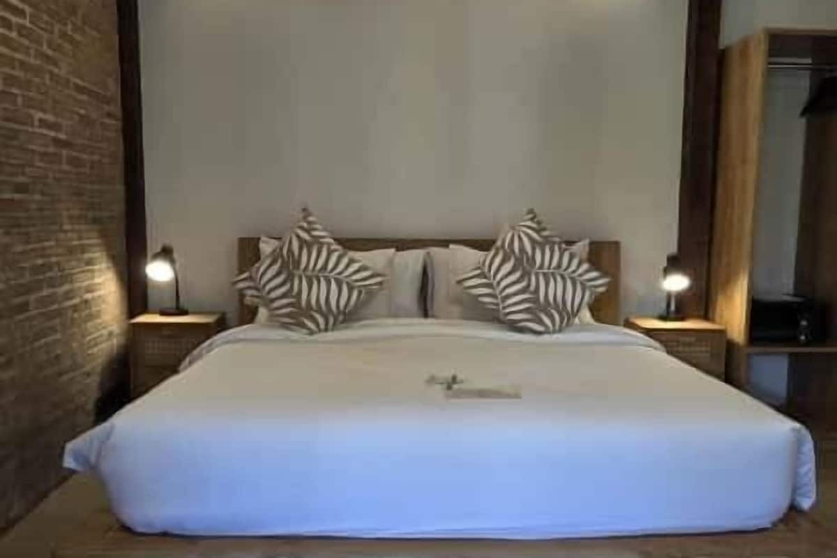 A bedroom with a bed, wooden headboard, and two bedside tables with lamps.