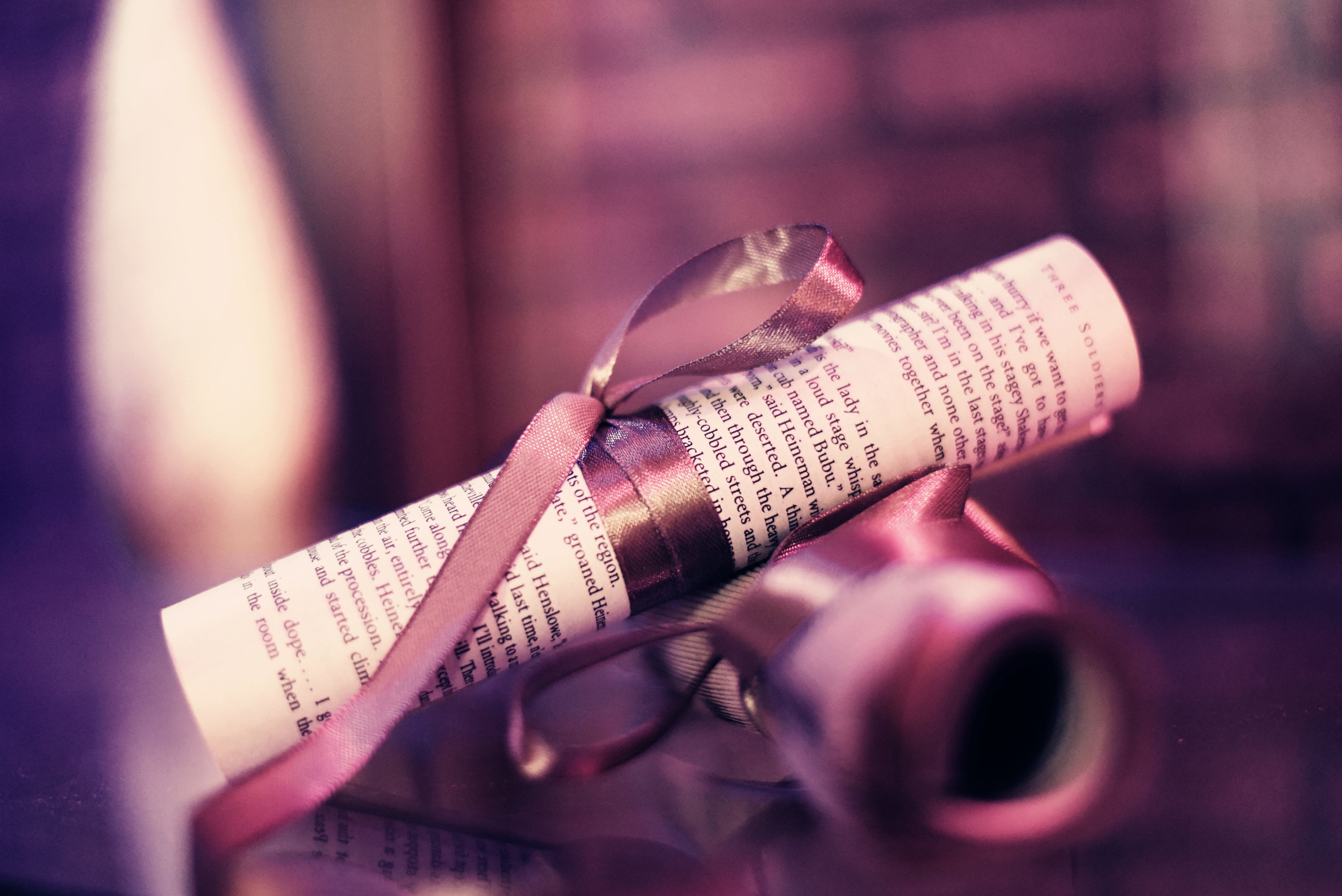 A rolled-up document secured with a ribbon, placed on a surface with a blurred background.