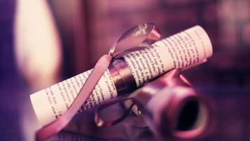 A rolled-up document secured with a ribbon, placed on a surface with a blurred background.