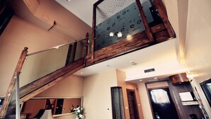 A modern interior with a wooden staircase, a large mirror, and a ceiling light fixture. - Harbin Bremen Jewish Culture Theme Hotel (Harbin)