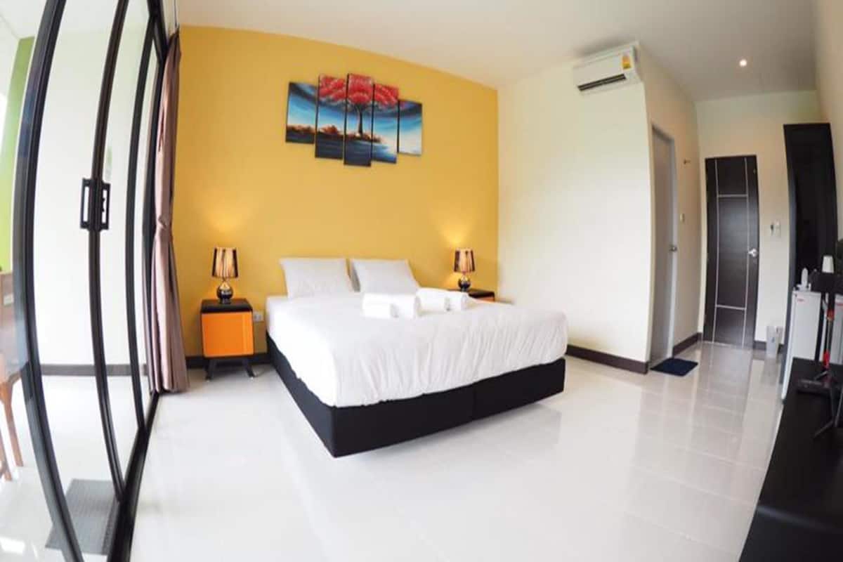 Une chambre d’hôtel moderne avec un grand lit, un tableau au mur et une porte sur le côté droit.