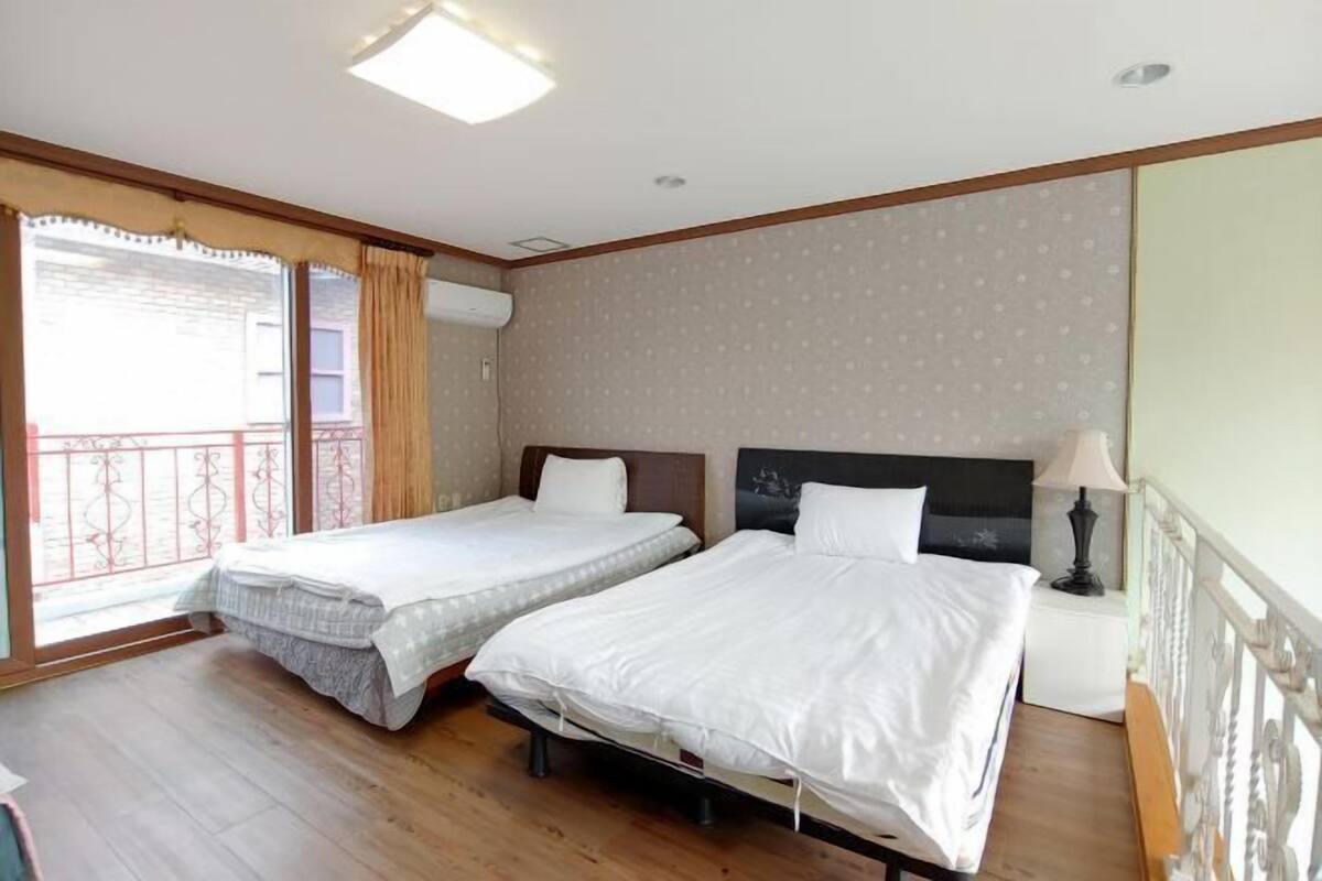 A hotel room with two beds, a balcony, and a window with curtains.