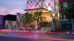 Un hotel moderno con fachada de diseño en patrón geométrico, una entrada destacada y un estacionamiento visible.