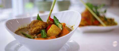 Un plat contenant divers légumes et un morceau de viande, servi dans une assiette blanche.