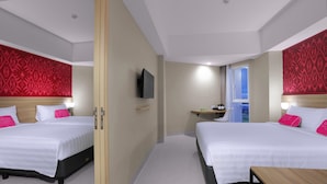 Habitación de hotel con dos camas, un televisor montado en la pared, un escritorio pequeño con una silla y una ventana que ofrece vistas.