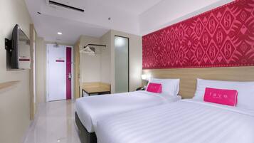 A hotel room with two beds, a large mirror, a wardrobe, and a patterned wall.