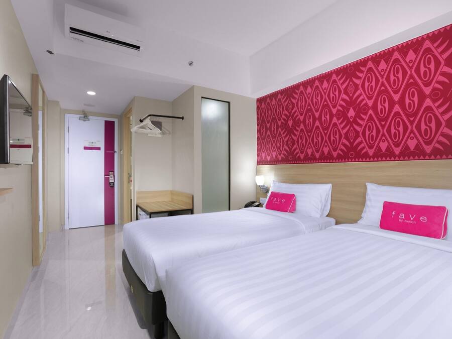 A hotel room with two beds, a large mirror, a wardrobe, and a patterned wall.