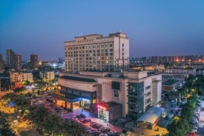 A multi-story hotel with a parking lot and adjacent commercial buildings. - Meigaomei International Hotel (Kunshan Lujia) (Kunshan)