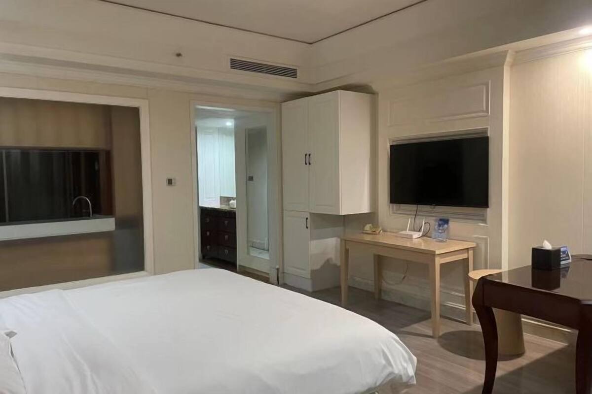 A hotel room with a bed, a desk, a TV, and a wardrobe.
