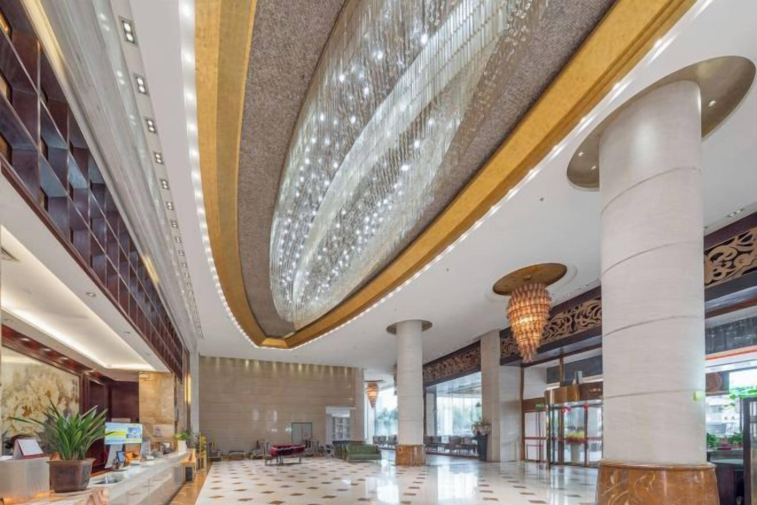 A spacious lobby with a high ceiling, large columns, and a chandelier.