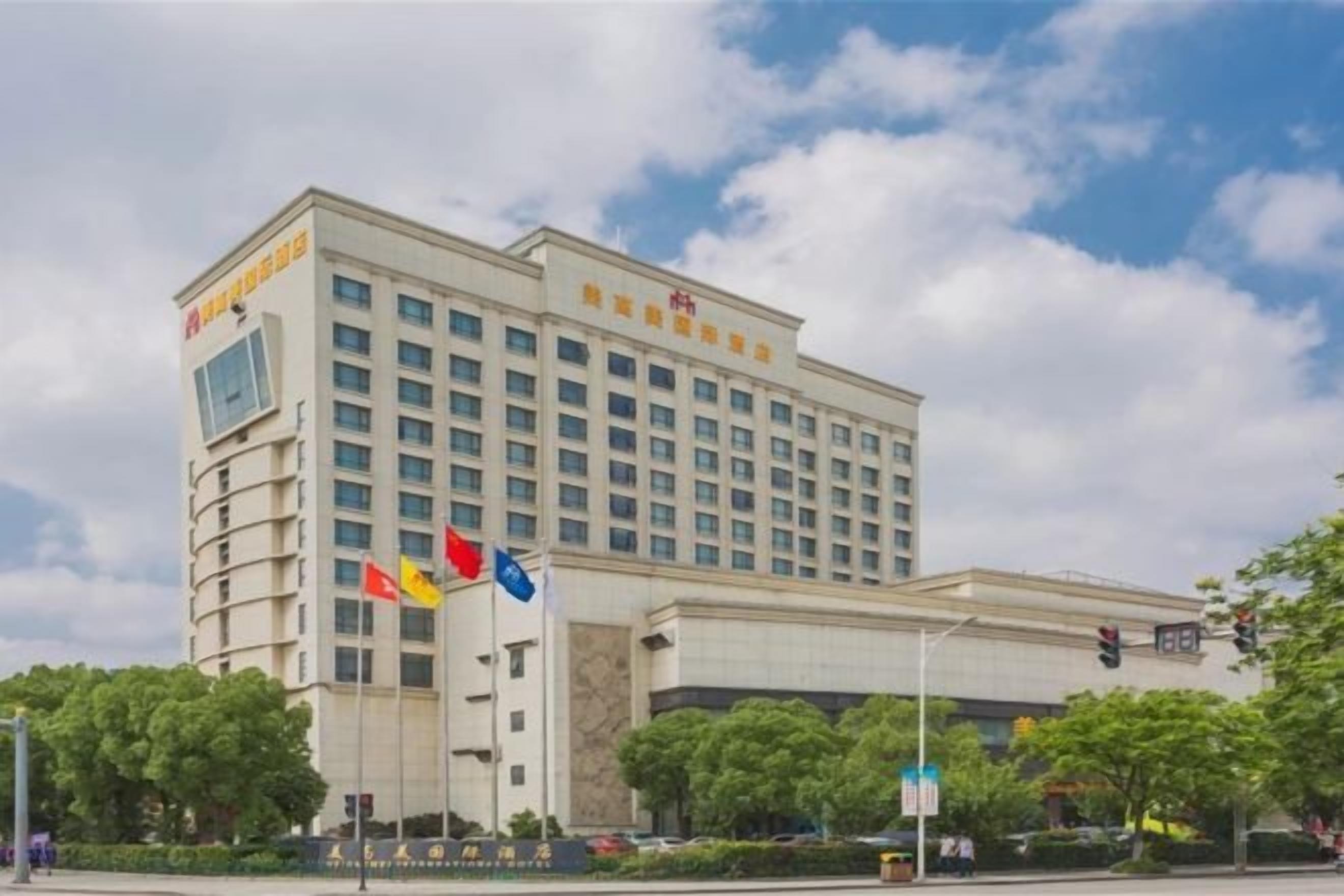 A large hotel building with multiple floors, flagpoles, and a clear sky.