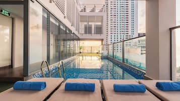 Una piscina al aire libre, sombrillas, sillones reclinables de piscina